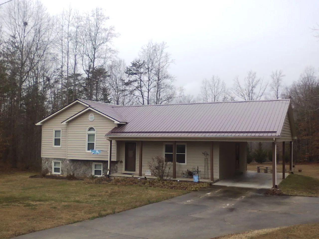 Burgundy metal roof on a tan split level home with an attached carport in Troy
